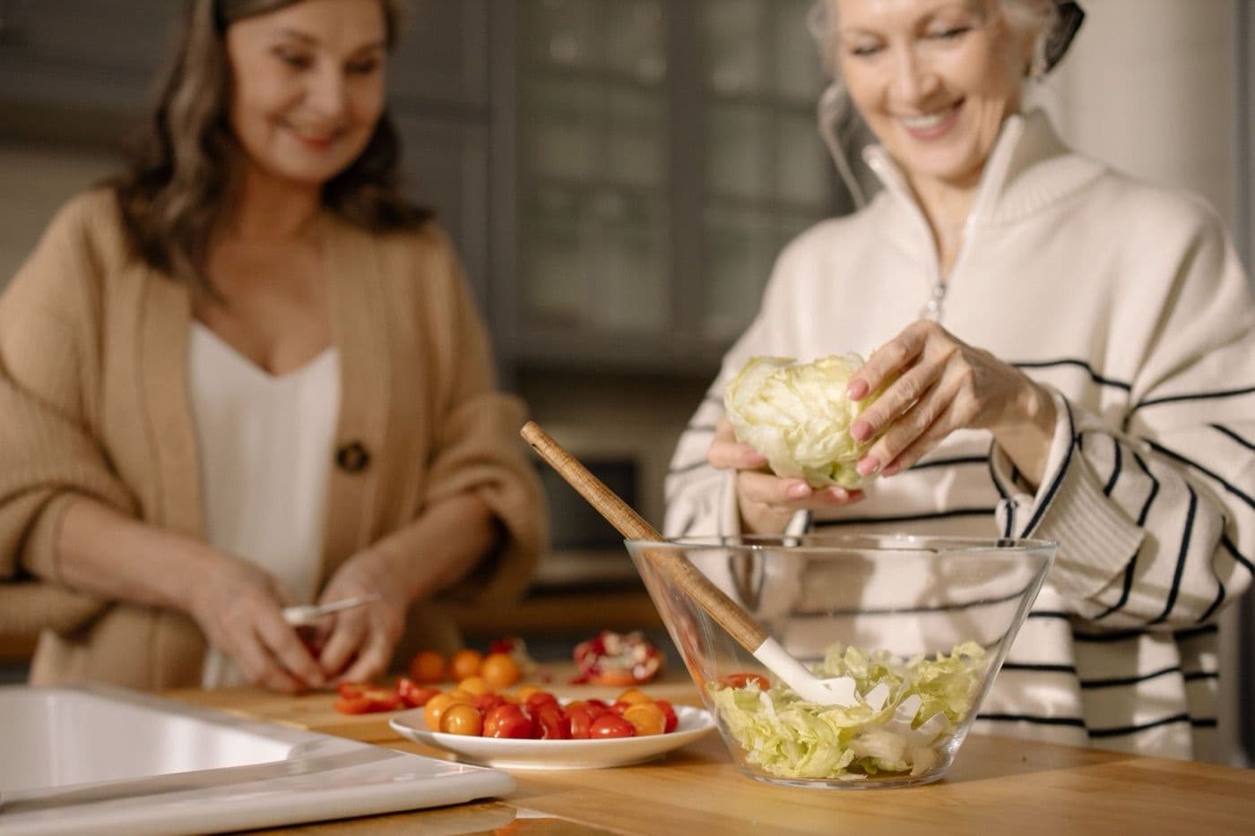 Two women preparing a salad together at a kitchen counter